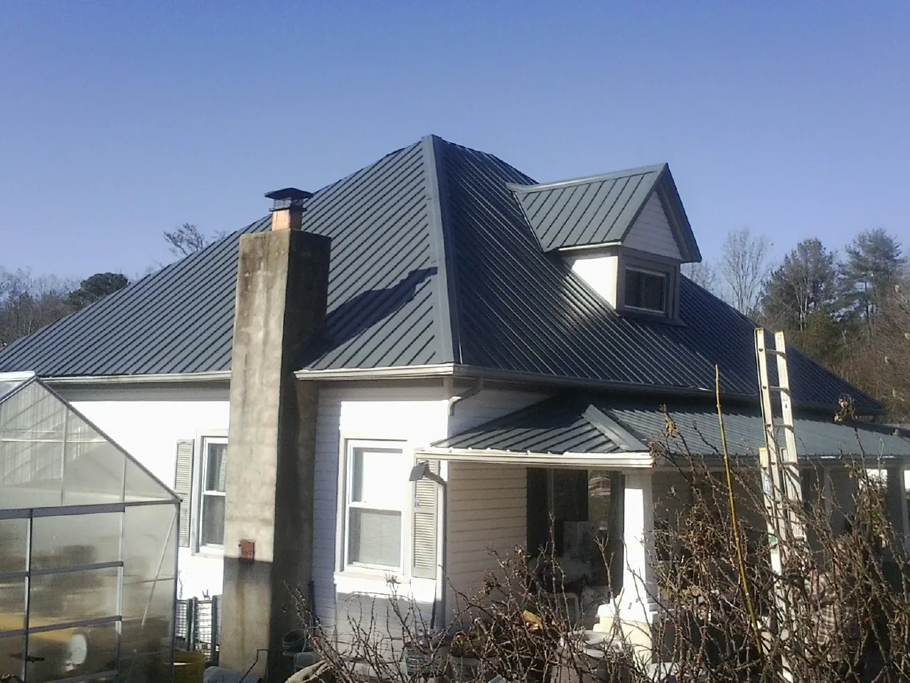 Dark blue standing seam metal roof on a white farmhouse with dormer — Slate & Tile Roof Repair by Roofing Brothers in Dixon Springs