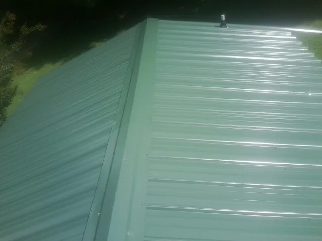 New green metal panels meeting at the ridge of a roof — Flat Roof Repair work by our crew in Dixon Springs