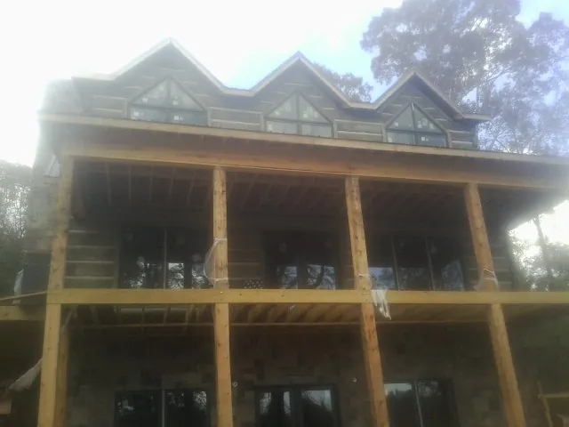 Dormers and porch framing on a large log home under construction — Roof Coating work by our crew in Dixon Springs