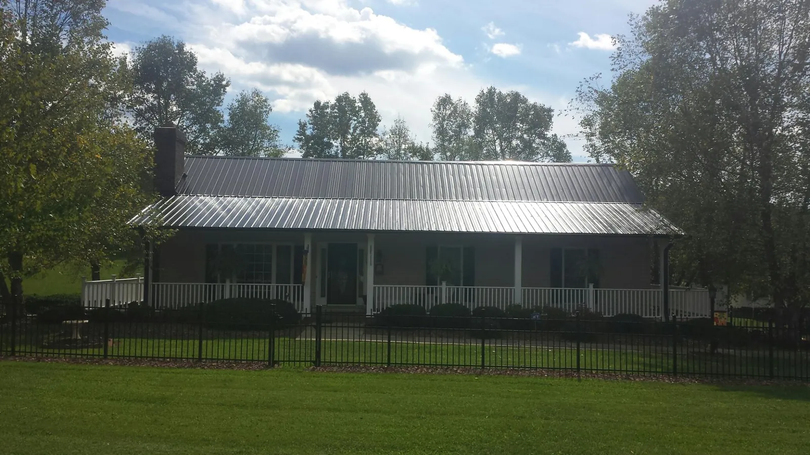 Gray metal roof on a brick ranch with a full width front porch — Gutter Guard Installation work by our crew in Dixon Springs