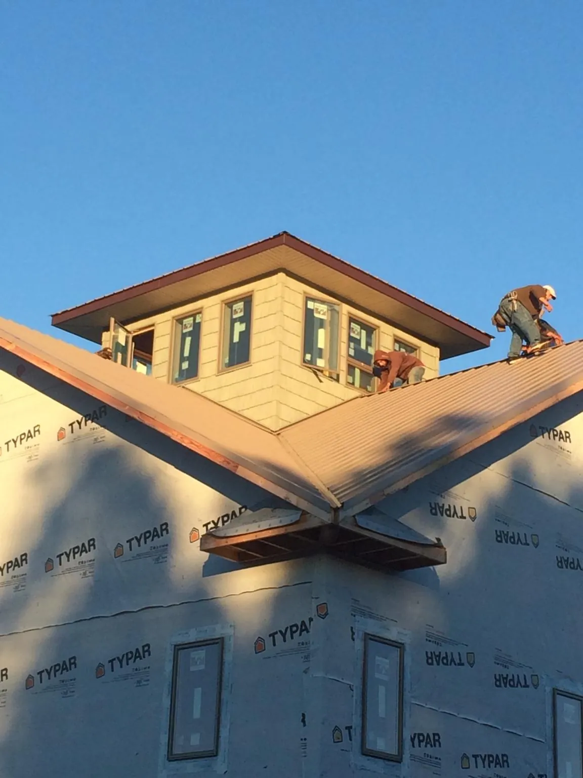 Roofers working around a rooftop cupola on a new metal roof at sunset — Roof Waterproofing in Dixon Springs by Roofing Brothers